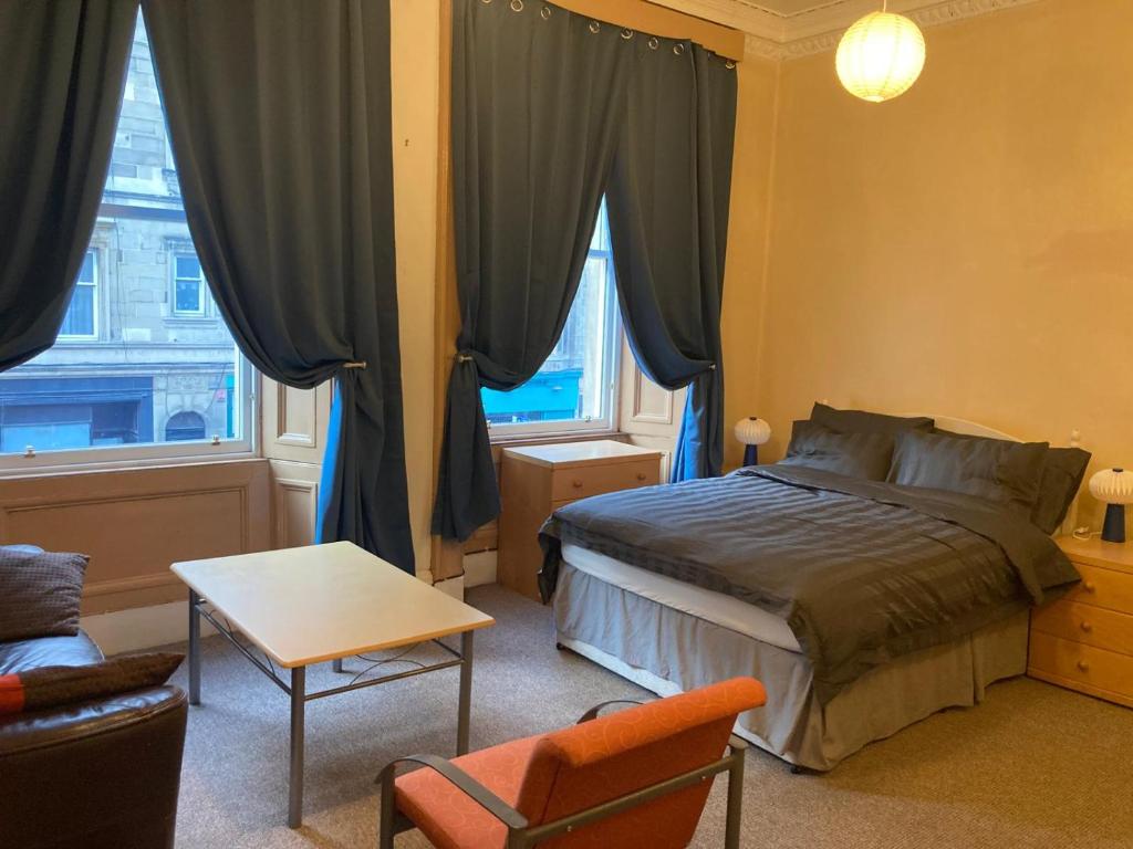 1 dormitorio con cama, silla y ventana en Gilmore Flat, en Edimburgo