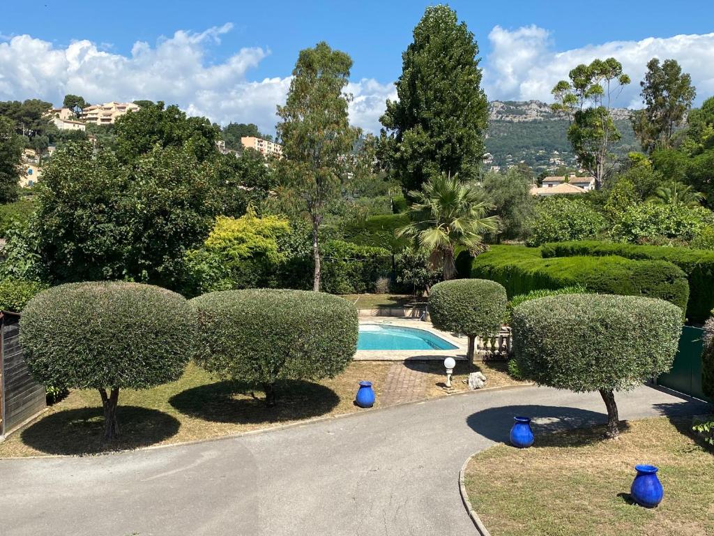 une piscine dans un jardin avec des arbres et des buissons dans l'établissement Les Jarres Bleues - Haut de Villa, à Vence