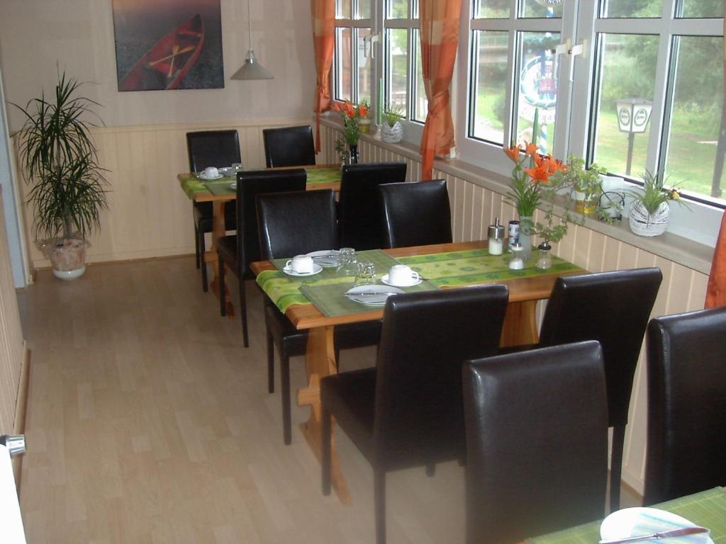 ein Esszimmer mit einem Tisch, Stühlen und Fenstern in der Unterkunft Zur Alten Fuldaschleife in Guxhagen