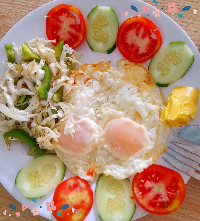 a plate of food with a fried egg and vegetables at Hugo's Family in Da Lat