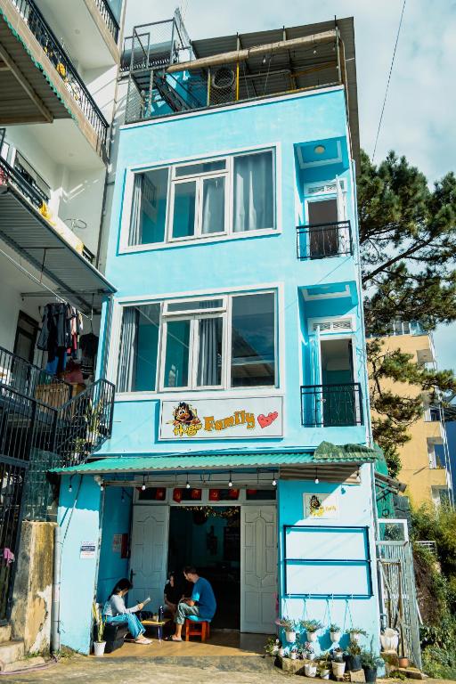 a blue building with people sitting outside of it at Hugo's Family in Da Lat
