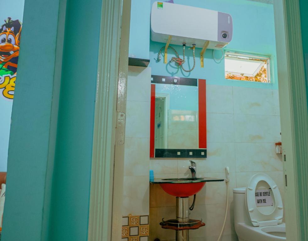 a bathroom with a toilet and a sink and a mirror at Hugo's Family in Da Lat