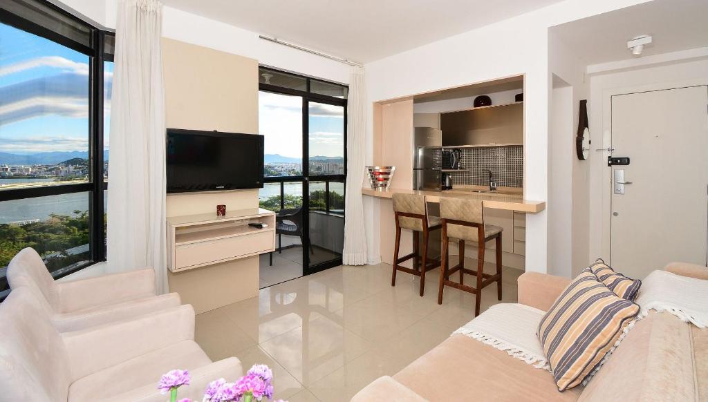 sala de estar con sofá y cocina con ventana grande en Flat com Vista para a Ponte Hercílio Luz - CEN005, en Florianópolis
