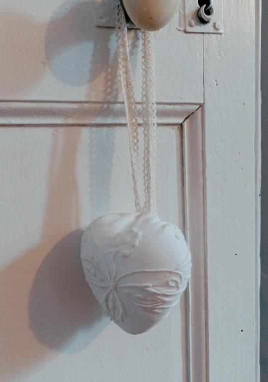 un objet blanc suspendu à une porte avec une chaîne dans l'établissement Maison Belle Croix, à Châtillon-Coligny