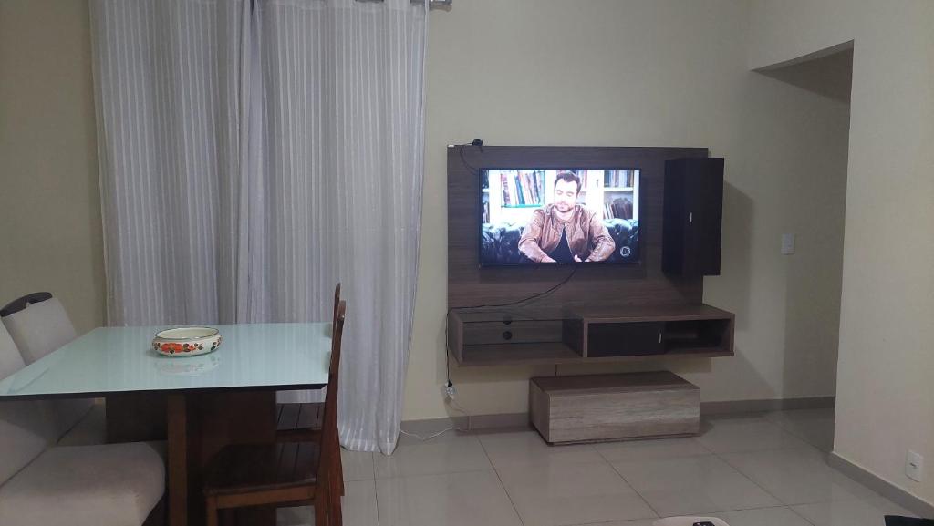 a living room with a tv and a table with a table at Apartamento Campos dos Goytacazes de 3 quartos com ar condicionado in Campos dos Goytacazes