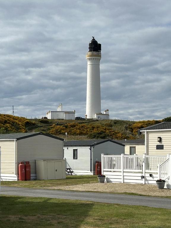 a lighthouse sitting on top of a hill with buildings at A13 - Beach Haven at Silversands in Lossiemouth