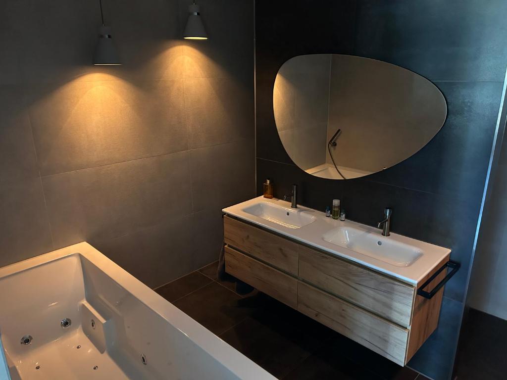 a bathroom with a tub and a sink and a mirror at B & B Huize Hertog met Whirlpool in Apeldoorn