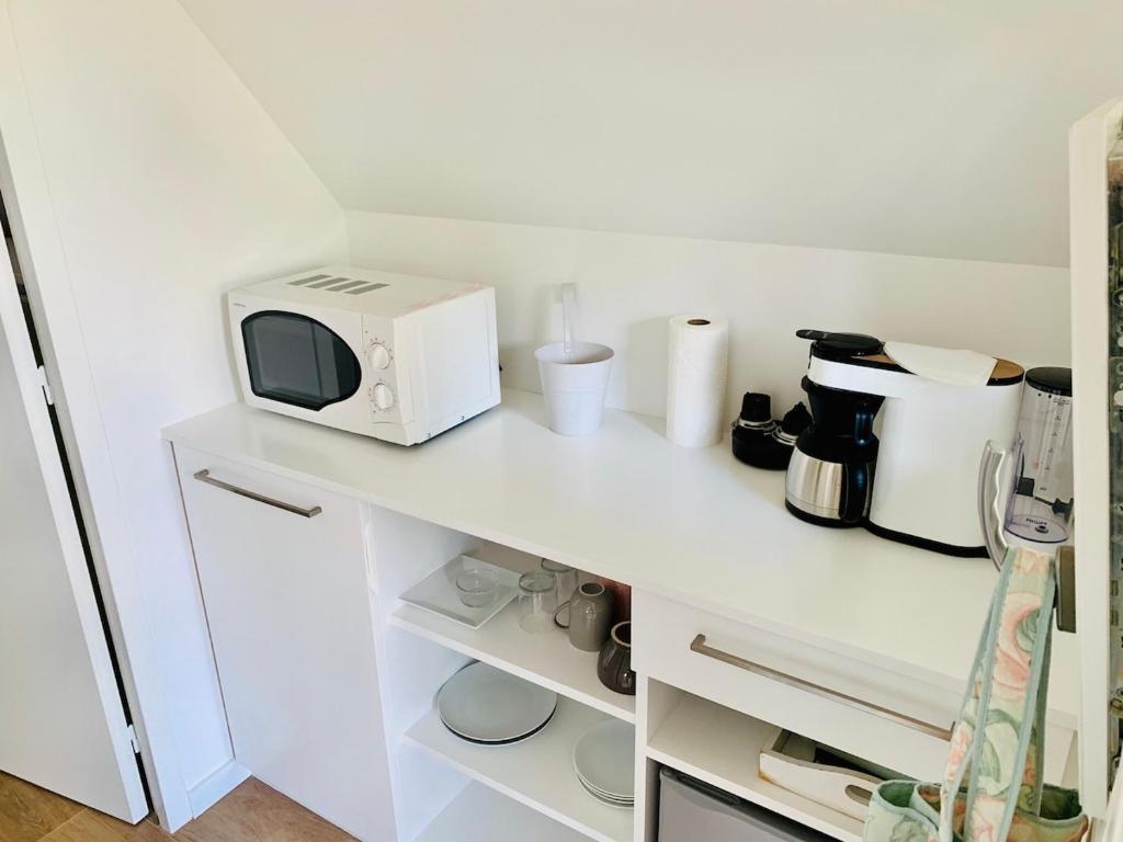 - un four micro-ondes installé sur un comptoir blanc dans la cuisine dans l'établissement Nice Cottage - Minimum 3 nuits, à La Baule