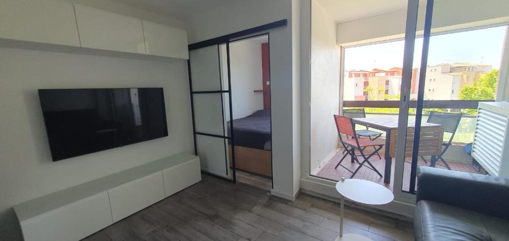un salon avec une télévision et une table avec des chaises dans l'établissement Studio rénové en 2025 à la marina, au Cap d'Agde