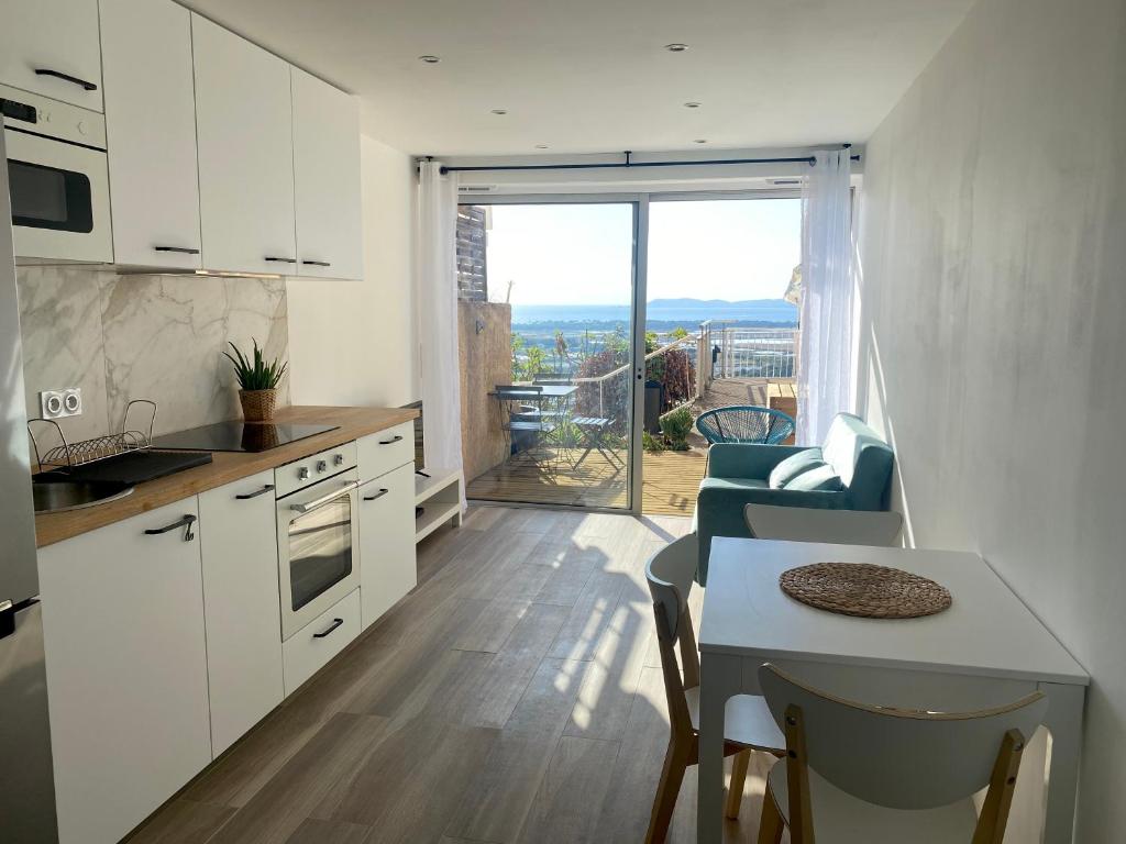 une cuisine avec des placards blancs et une table avec vue dans l'établissement Studio vue mer au Mont des Oiseaux à Hyères, à Hyères
