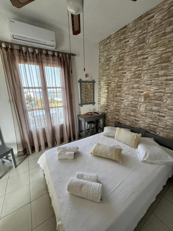 a large white bed in a room with a brick wall at Panagiotis Rooms in Naousa