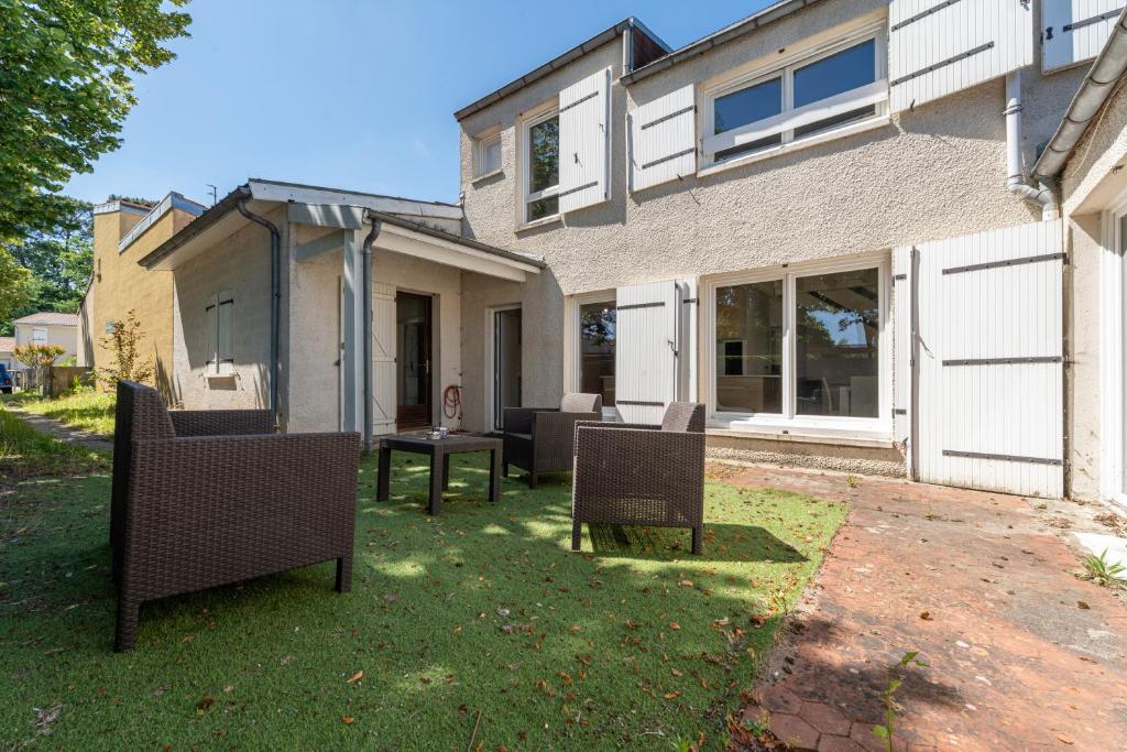 un patio avec des chaises et une table devant une maison dans l'établissement L'Ecrin Vert - Maison 6 Chambres 12 Pers à Bdx, à Gradignan