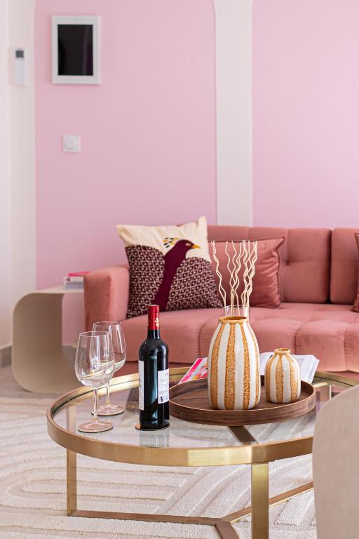 un salon avec un canapé rose et une table avec des verres à vin dans l'établissement Rosa Vida - Retro Chic, à Cannes