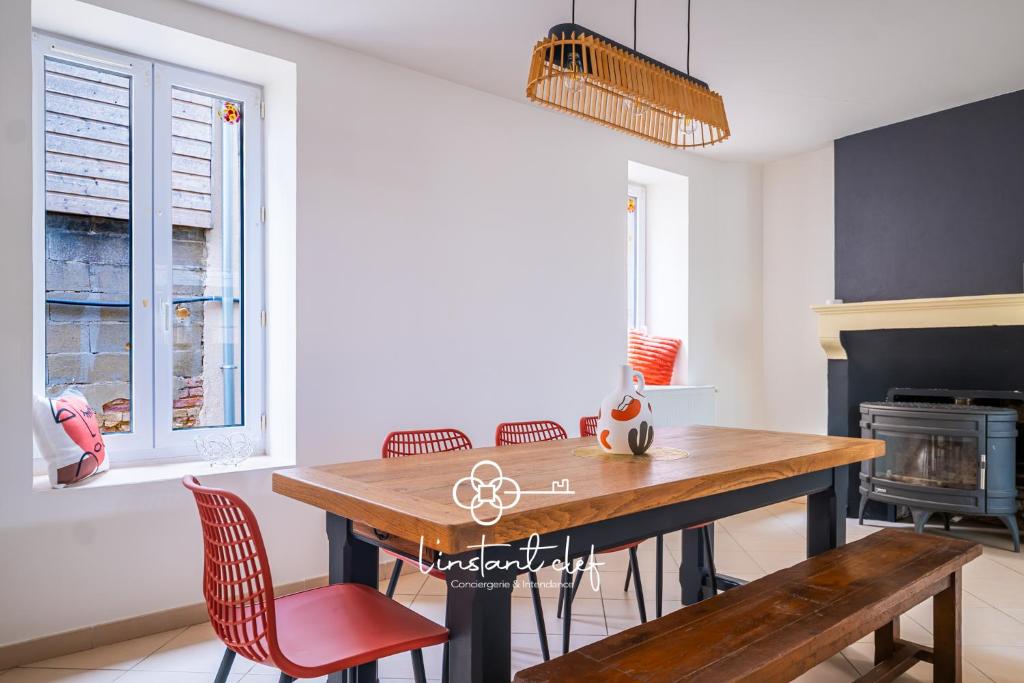 een eetkamer met een houten tafel en stoelen bij Douceur bucolique, jardin & mezzanine cosy in Parigné-lʼÉvêque