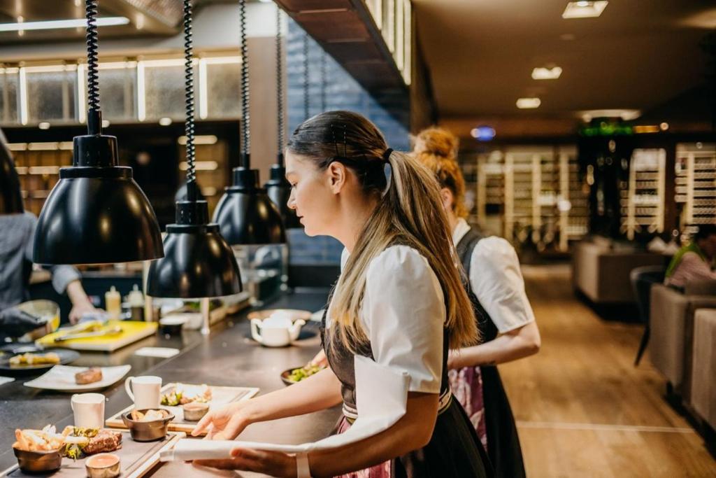a woman standing in a kitchen preparing food at Grand Tirolia Kitzbühel - Member of Hommage Luxury Hotels Collection in Kitzbühel