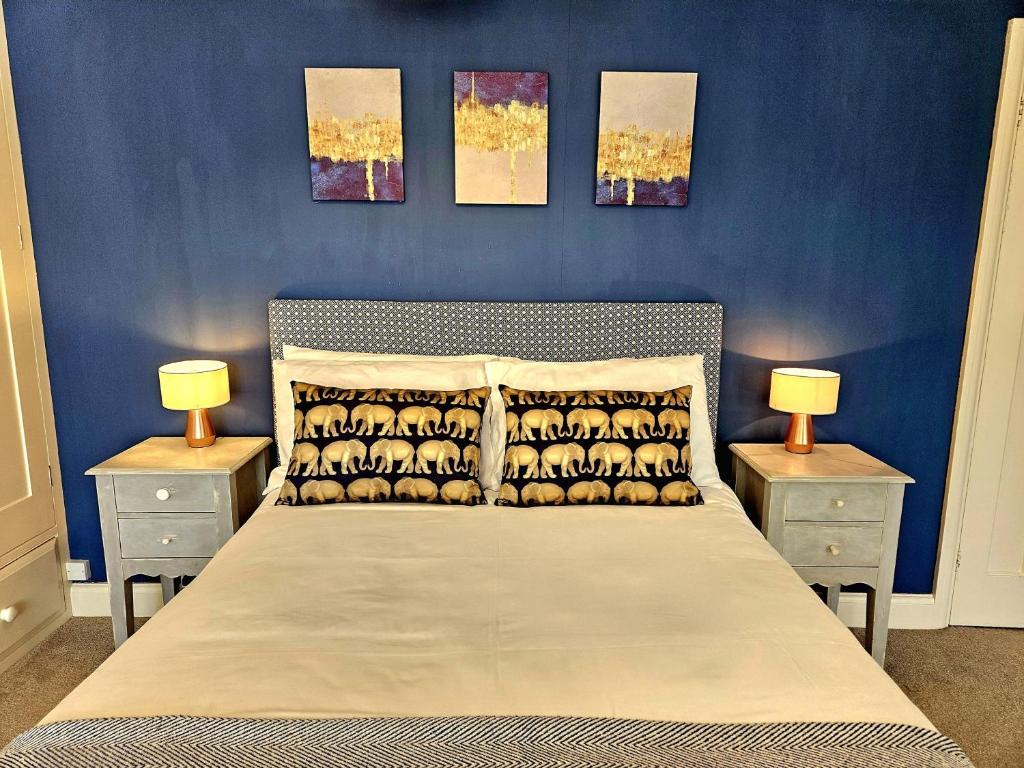 a bedroom with blue walls and a bed with two night stands at Prospect Cottage in Hythe