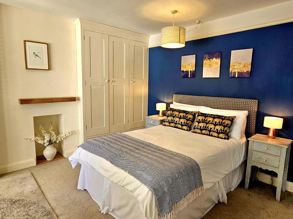 a bedroom with a bed with a blue wall at Prospect Cottage in Hythe