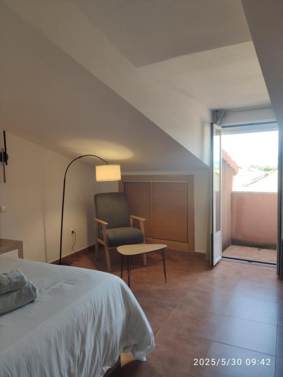 Un dormitorio con una cama, una silla y una mesa. en Apartamentos Joli, en Olivares de Duero