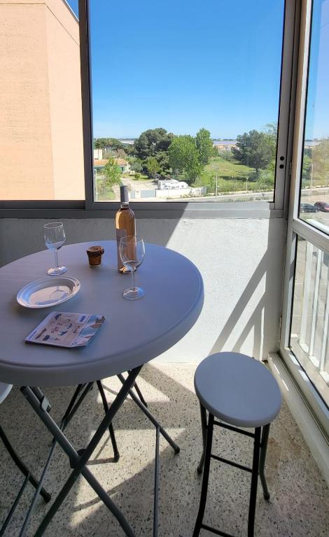 Una mesa azul con dos copas de vino y una ventana. en La Frégate Town Centre and Beach, en Le Grau-du-Roi