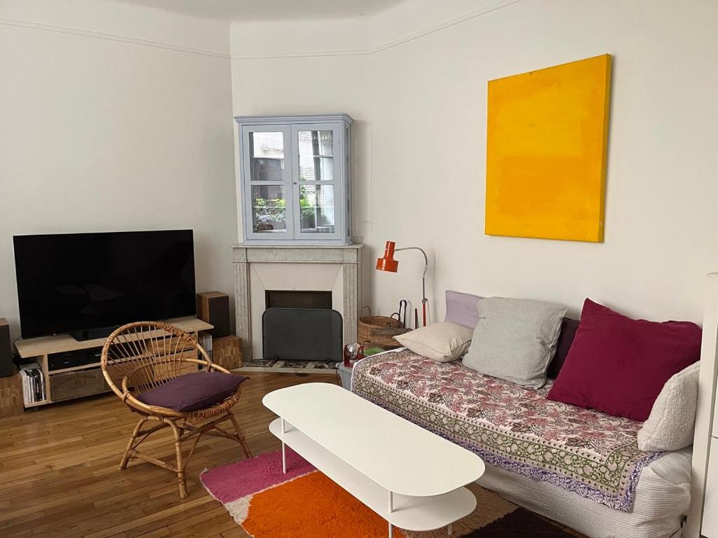un salon avec un canapé et une télévision dans l'établissement Comme une petite maison, à Paris