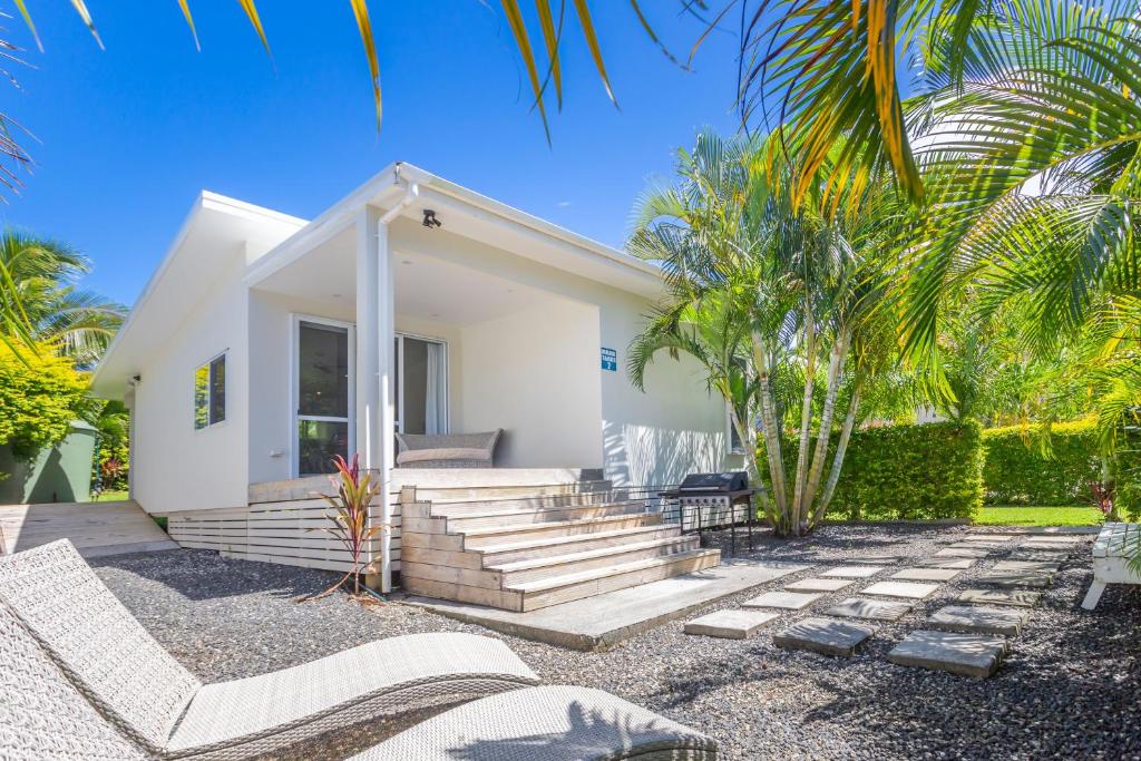 a white house with stairs and palm trees at Mama Taras Bungalows in Rarotonga
