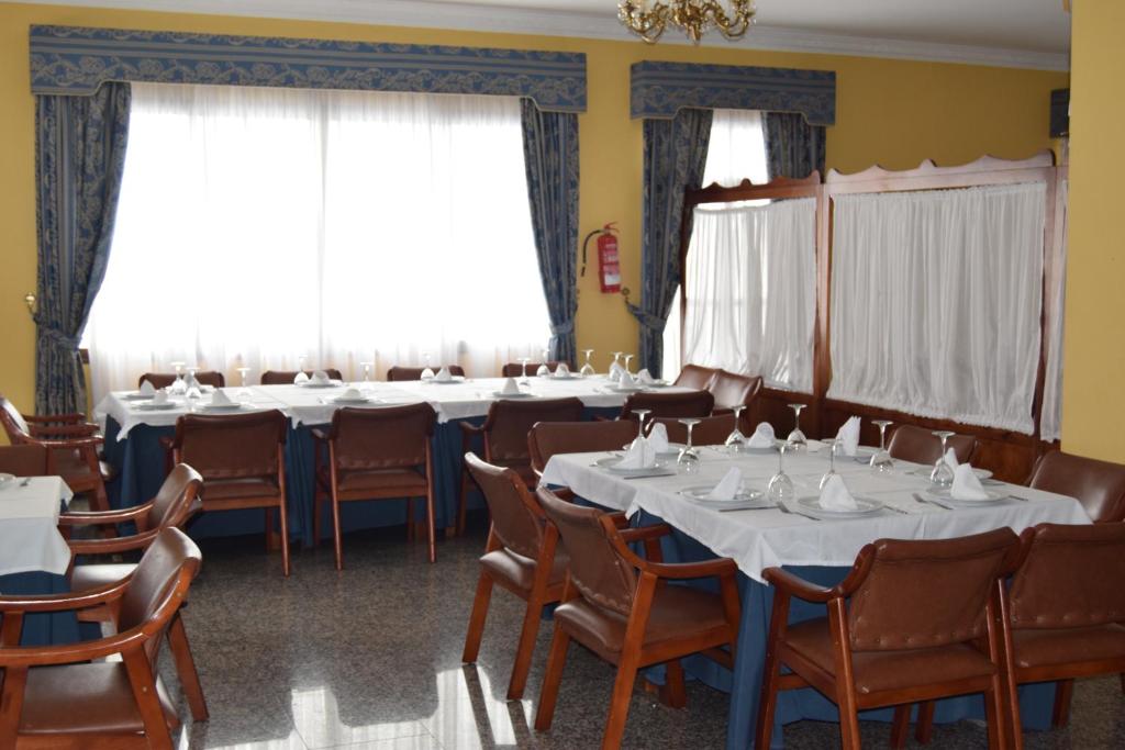 een conferentiezaal met tafels, stoelen en ramen bij Hotel Río Seco in Pedrera