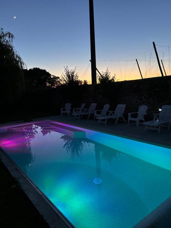 - une piscine avec des chaises et un coucher de soleil en arrière-plan dans l'établissement Le Colibri - Domaine de la Houblette, à Challans