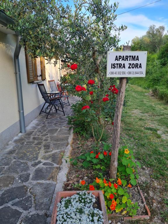 a sign in a garden with flowers in front of a house at Apartma Istra Zora in Sečovlje