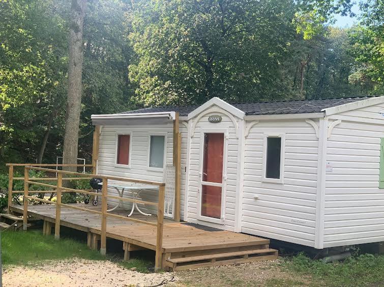 une maison blanche avec une terrasse en bois dans la cour dans l'établissement Mobil home paisible, à Saint-Chéron