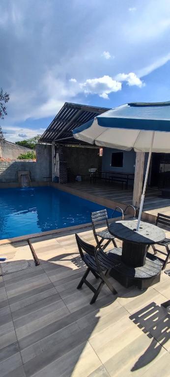 a table and chairs with an umbrella and a pool at Rancho do Vale in Carlópolis