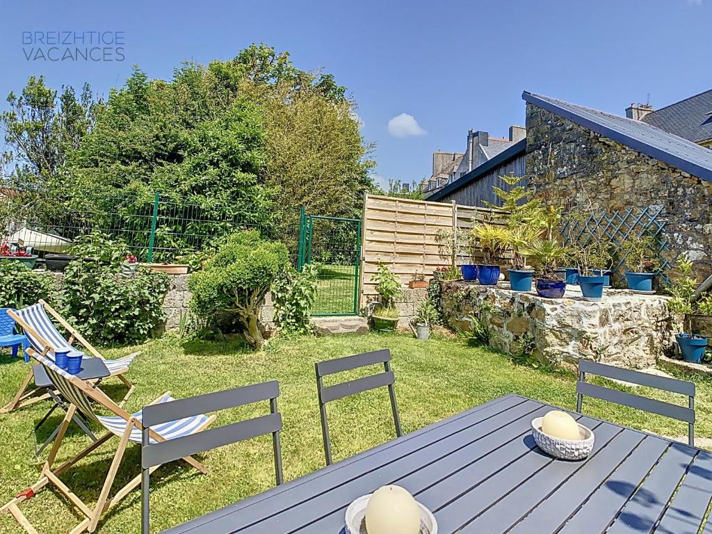 un patio con tavolo e sedie in un cortile di Maison Ty Gwen - Centre-ville avec jardin et proche de la plage a Crozon