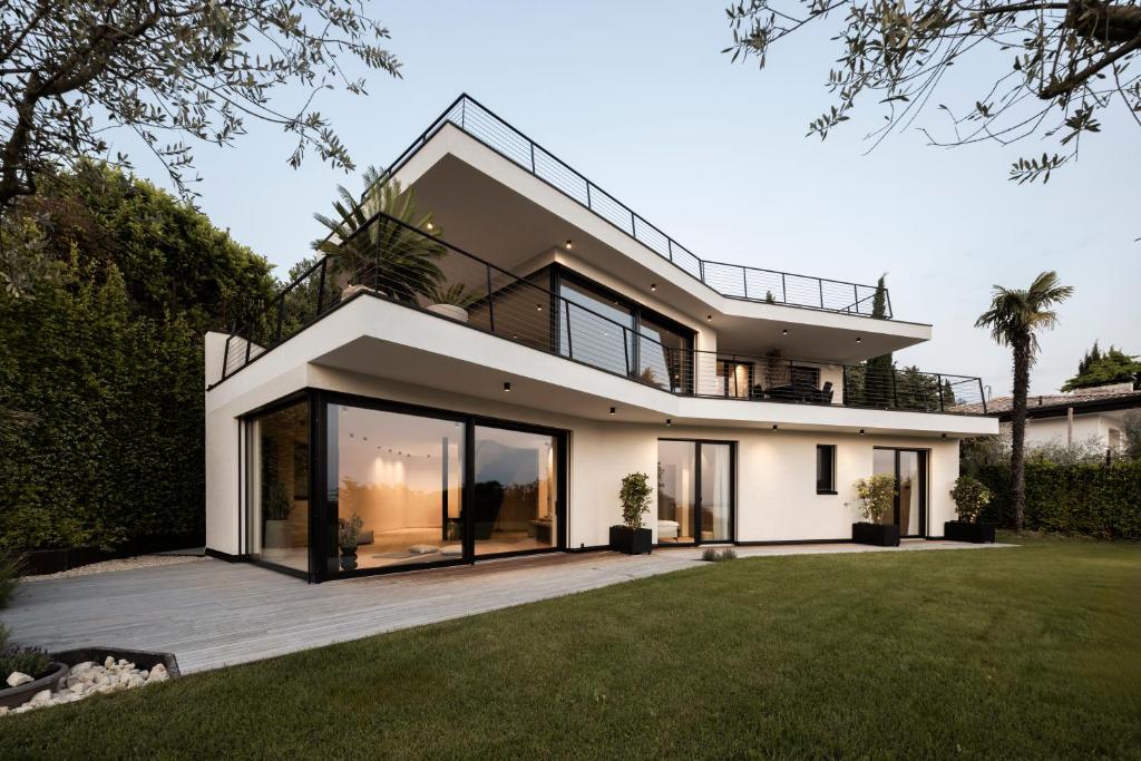 a modern house with a large glass facade at My Summer Lakeside Villa with Pool and Hot Tub in Bardolino