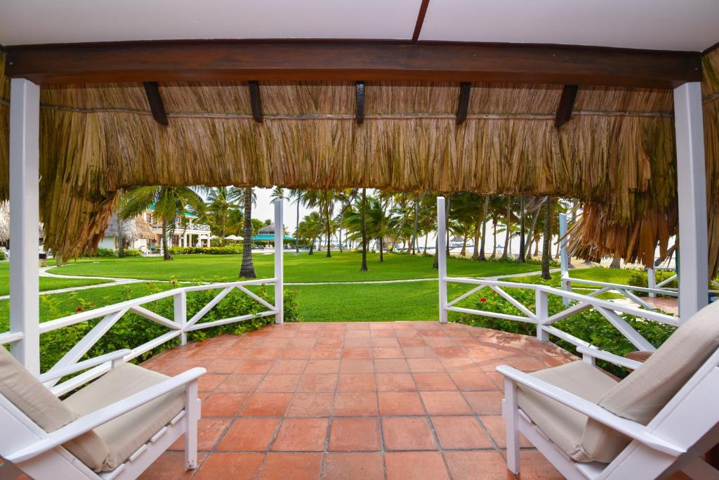 a pavilion with two chairs and a straw roof at Victoria House Resort & Spa in San Pedro