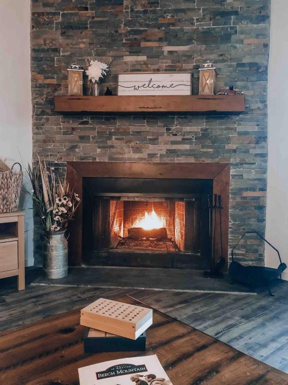 a brick fireplace with a fire in it at Beechview Condo in Beech Mountain