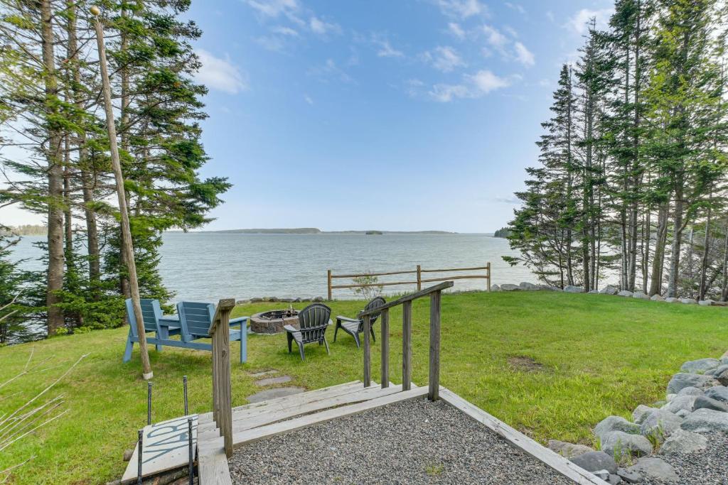 un portico con due sedie e un tavolo vicino all'acqua di Waterfront Roque Bluffs Hideaway with Private Beach a Machias