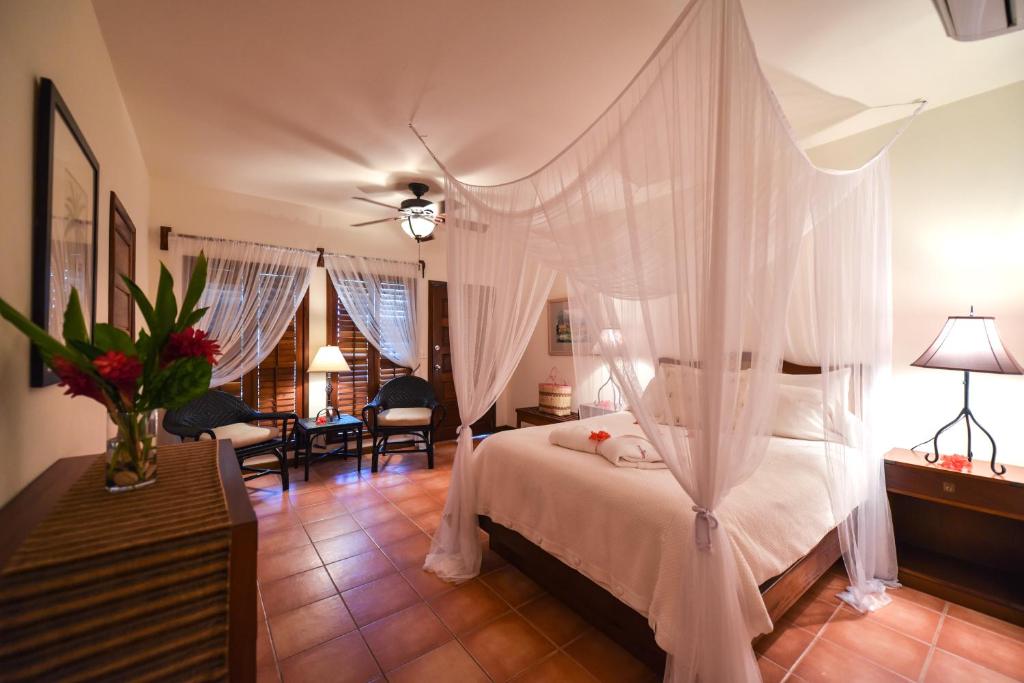 a bedroom with a white bed with a canopy at Victoria House Resort & Spa in San Pedro