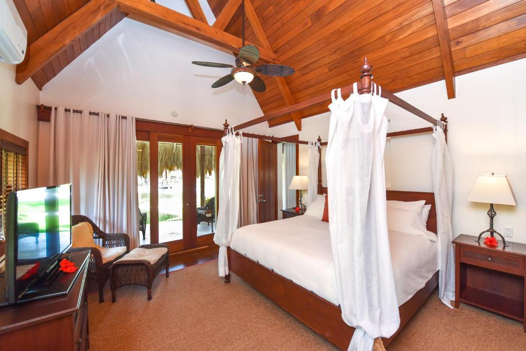 a bedroom with a bed with a ceiling fan and a television at Victoria House Resort & Spa in San Pedro