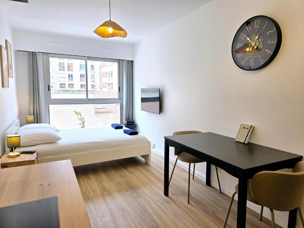 Cette chambre comprend un lit, une table et une horloge. dans l'établissement Cosy Apartments - Marseille Estiennes d'Orves - Hyper central students apartment close to metro and Vieux-Port, à Marseille