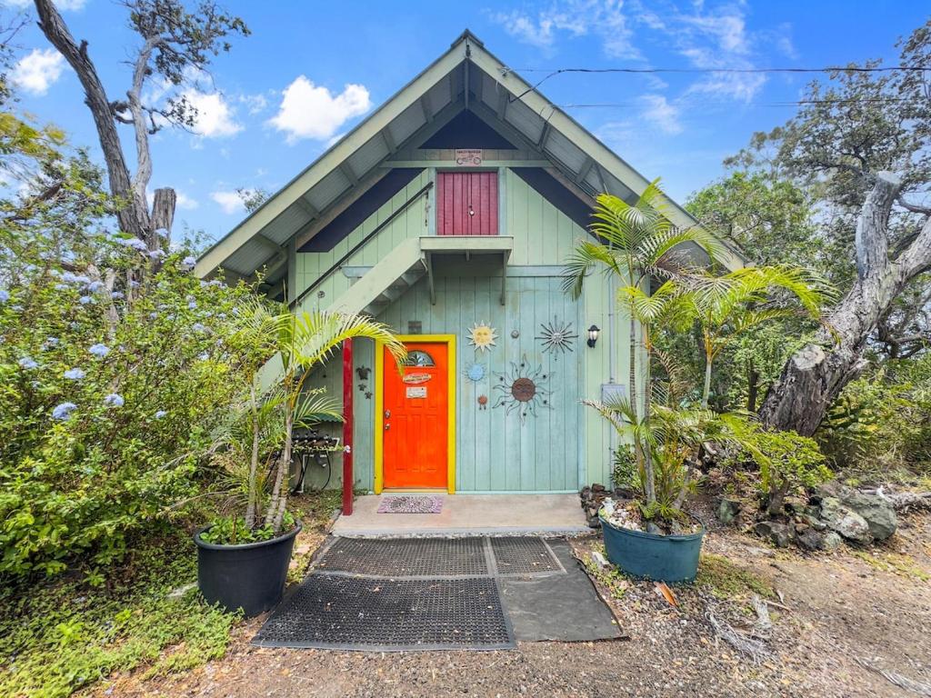 a green house with a red door and some plants at Best Ocean Views from Guesthouse in Hawaiian Ocean View Estates