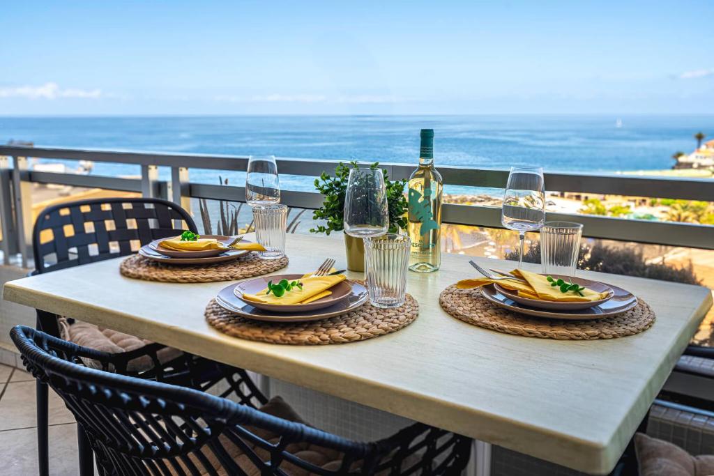 a table with plates of food and glasses of wine at Sol del Sur Ocean View in Puerto de Santiago