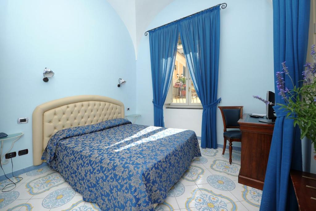 a bedroom with a bed and a desk and a window at B&B Palazzo Pisani in Amalfi
