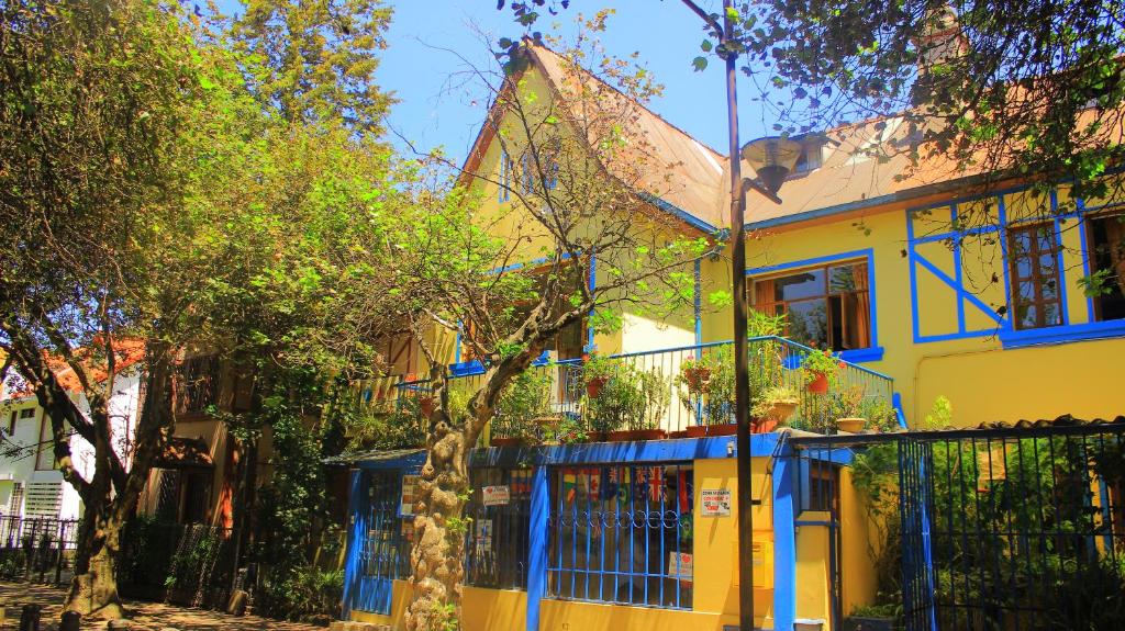 a yellow house with blue trim at Hostal Posada del Maple in Quito