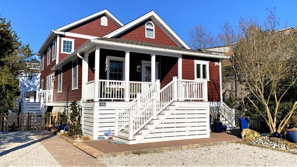 una casa roja con un porche delantero blanco en Sail Away, en Cape May Point