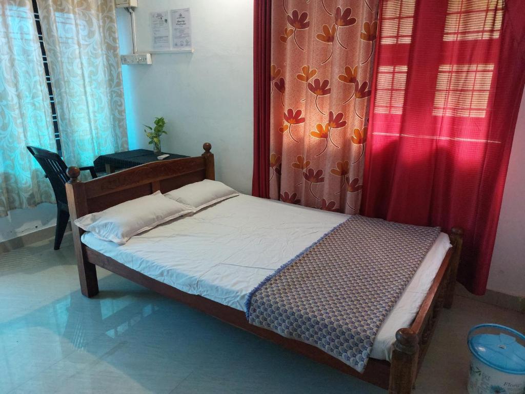 a small bed in a room with a red curtain at Nunu Homestay Guruvayoor in Guruvāyūr