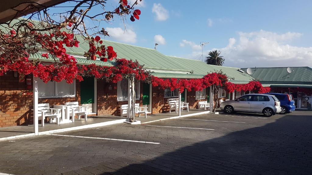 a car parked in front of a building with red flowers at Motel Homestead in Auckland