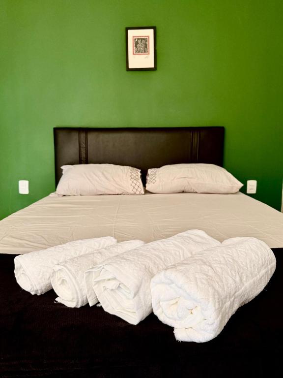a green bedroom with a large bed with white sheets at Loft Vava in Campina Grande