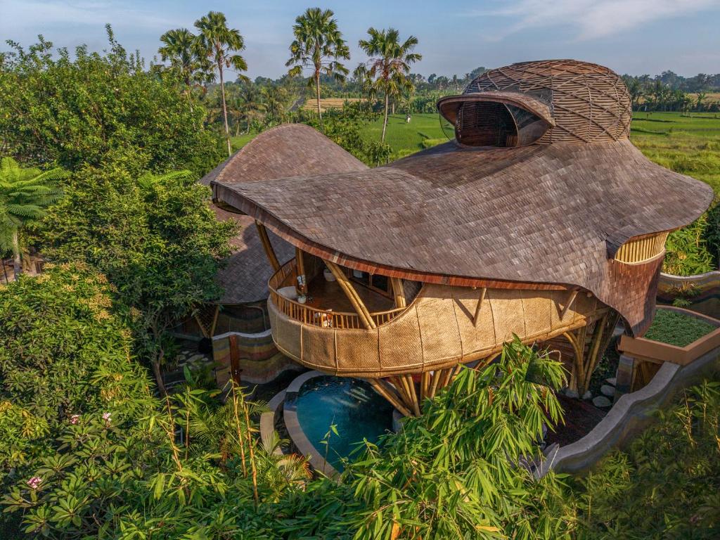 una piccola casa con un tetto in cima a un campo di Ulaman Eco Luxury Resort a Tabanan