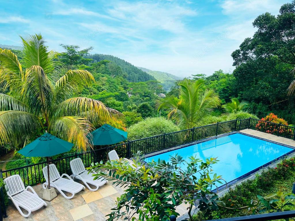 a swimming pool with chairs and umbrellas on a balcony at Grand Hills kandy in Kandy