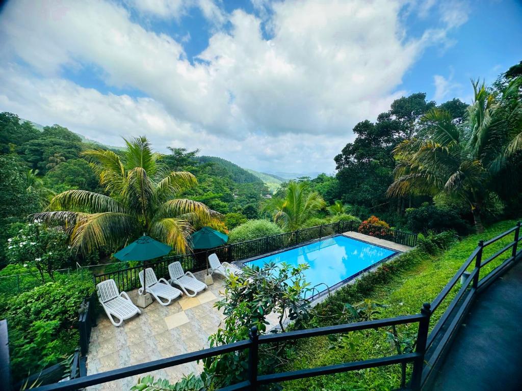 a swimming pool with chairs and a view of the mountains at Grand Hills kandy in Kandy