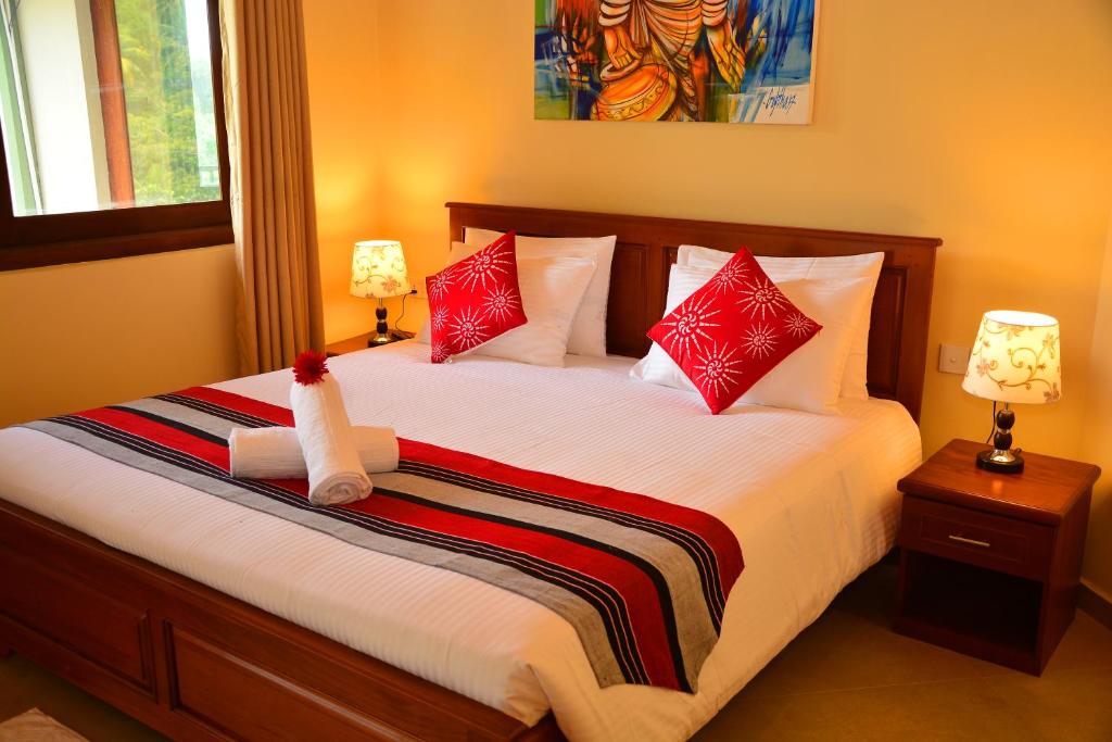a bedroom with a large bed with red pillows at Grand Hills kandy in Kandy